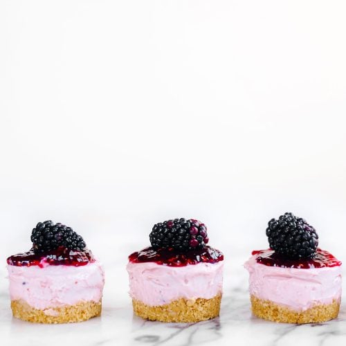 three No Bake Mini Blackberry Cheesecakes on a plain white background.