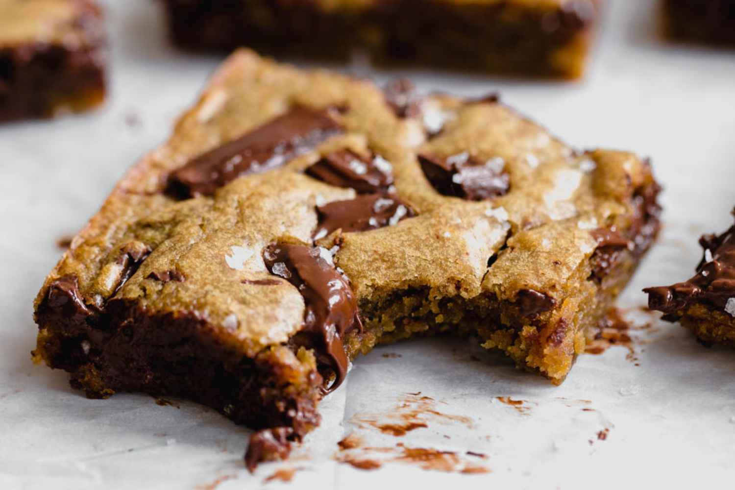 a slice of gooey chocolate chunk blondie with a bite taken out.