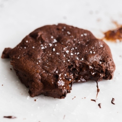 a double chocolate chip cookie on a white background, with a bite taken out.