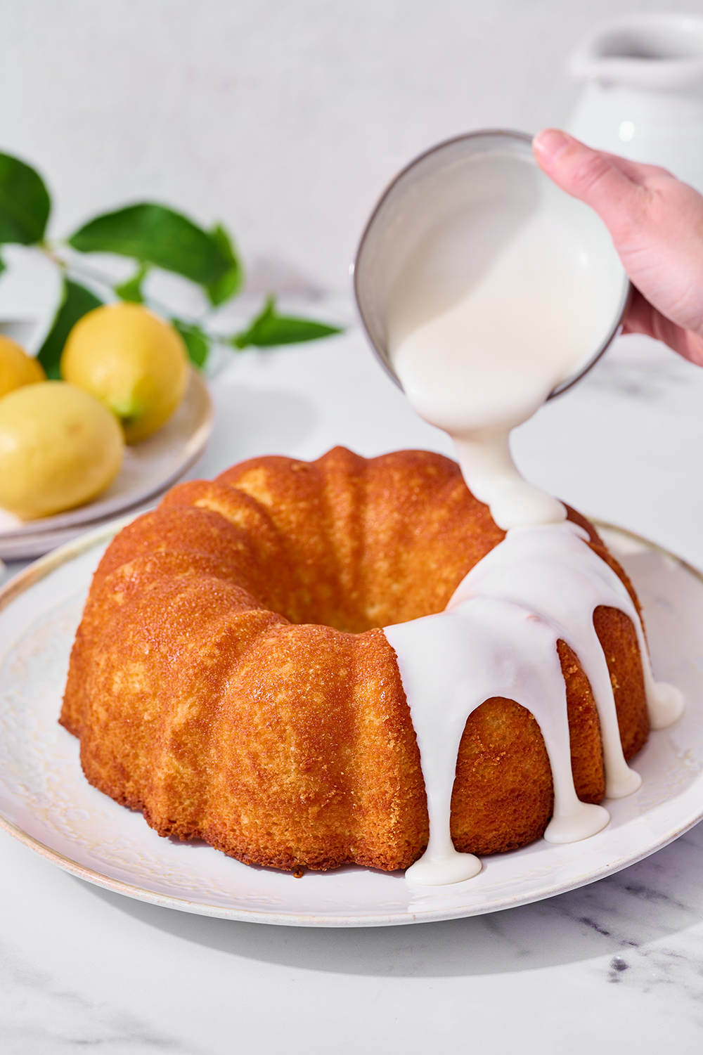glaze being drizzled onto freshly baked lemon bundt cake