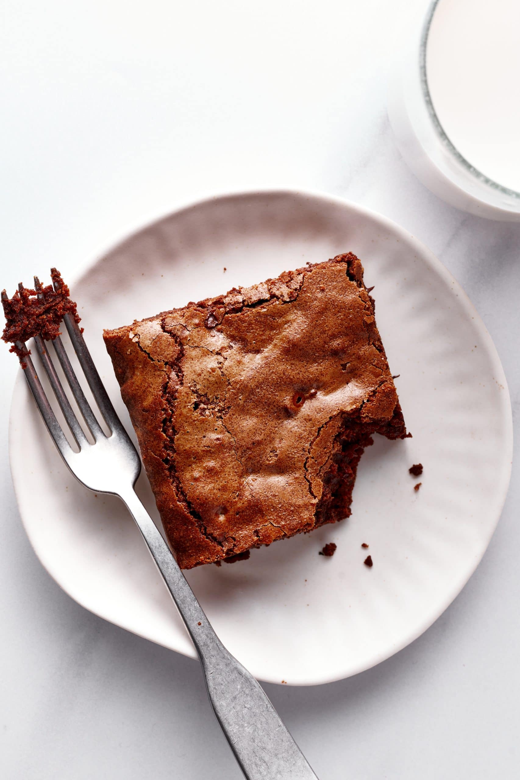 slice of brownie on a plate with a fork, with a bake taken out