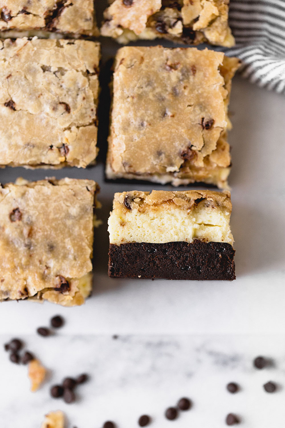 a few Brownie Bottom Cookie Dough Cheesecake bars, with one on its side to show the three distinct layers