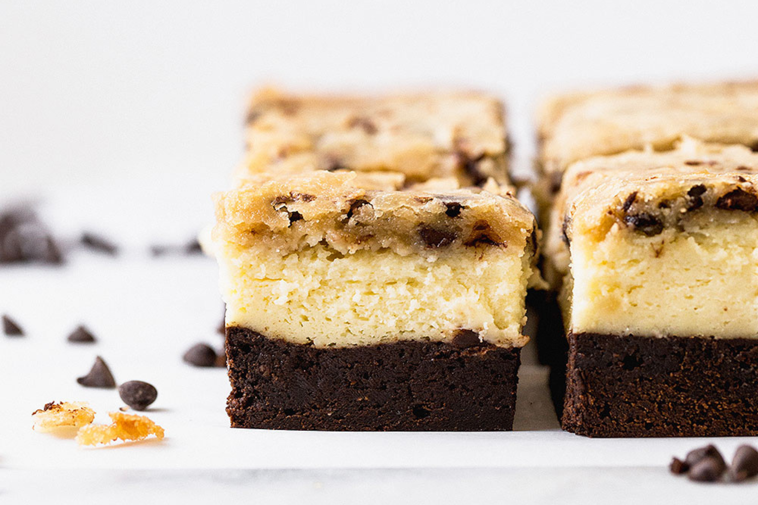 side view of Brownie Bottom Cookie Dough Cheesecake Bars, showing their three decadent layers
