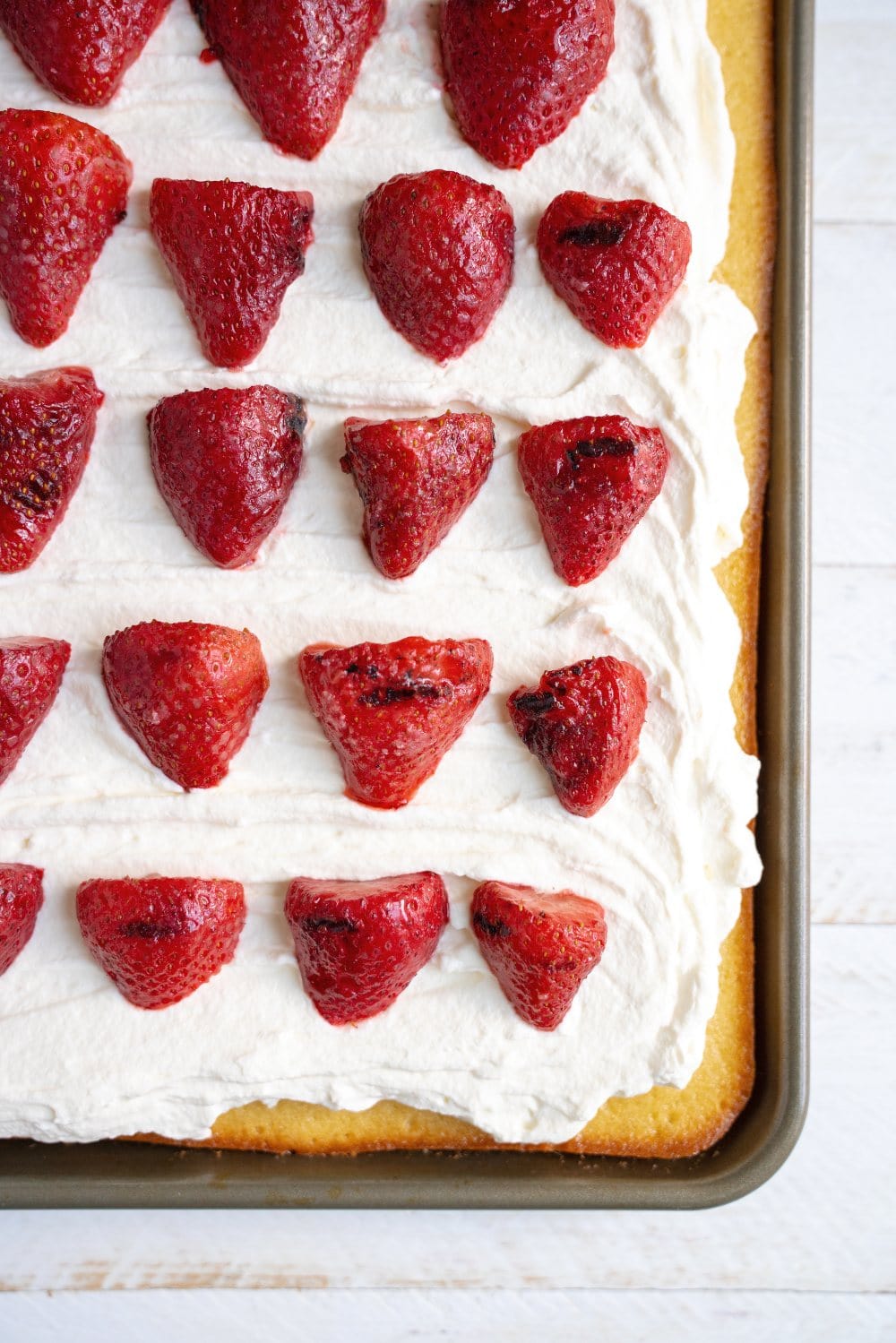 Vanilla Sheet Cake with Grilled Strawberries features an ultra moist, tender, and slightly spongy vanilla cake with fresh whipped cream and slightly smoky grilled strawberries on top. Perfect summer dessert for a crowd!