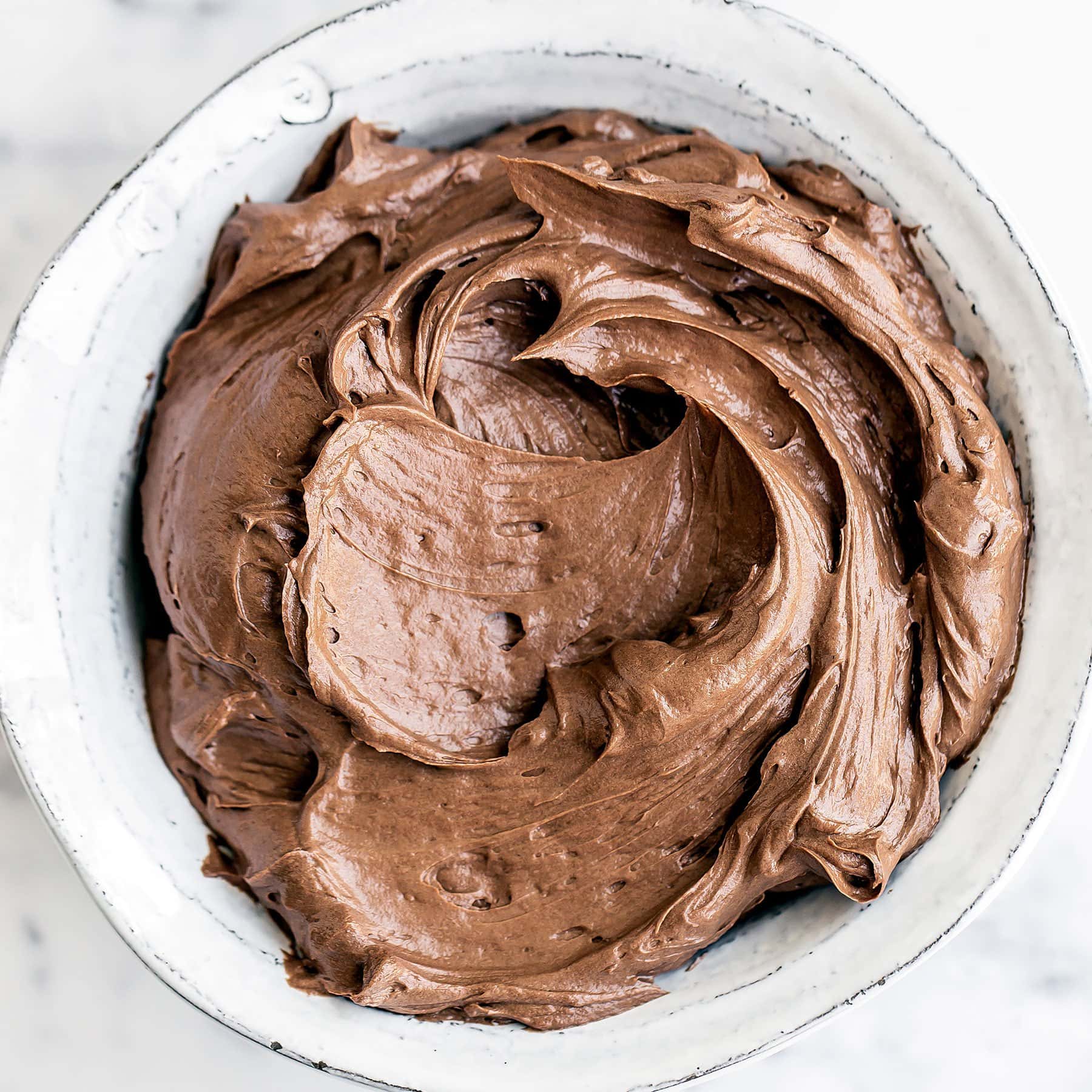 Ultra smooth, creamy, and perfectly sweet, this Chocolate Swiss Meringue Buttercream is quite possibly the BEST frosting you'll ever taste! Step by step photos AND how-to video included!