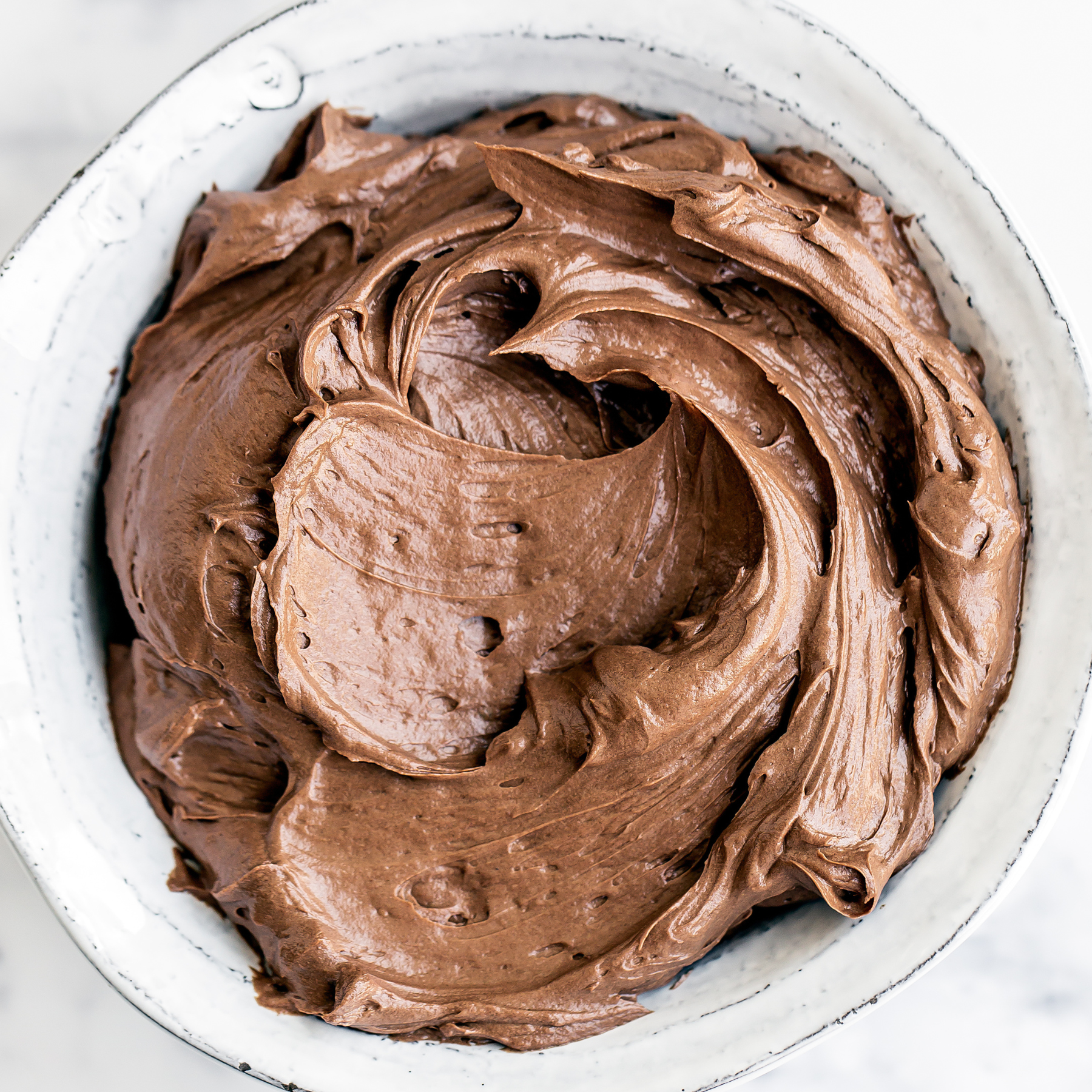 a bowl of chocolate swiss meringue buttercream frosting.