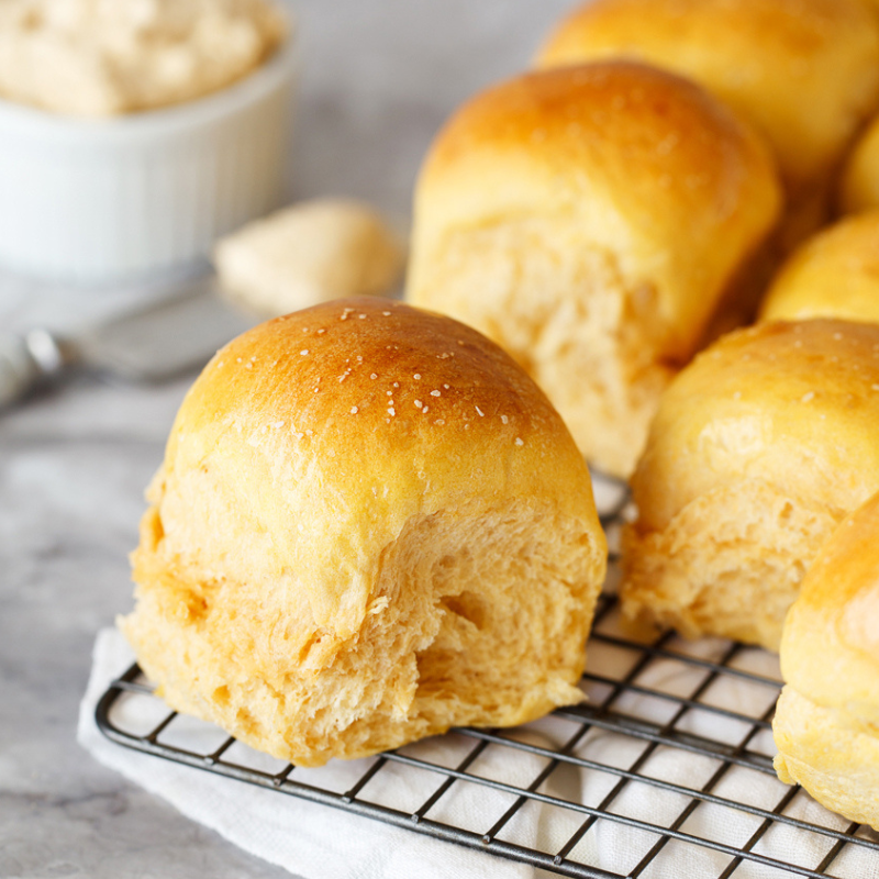 sweet potato dinner rolls cooling on a wire rack before serving.