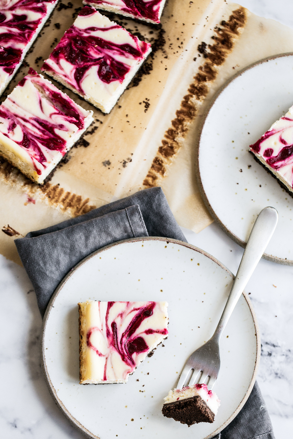 slices of Cranberry Swirl Cheesecake Bars being served onto plates with forks