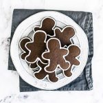 several gingerbread men cookies on a white plate with a blue napkin behind.