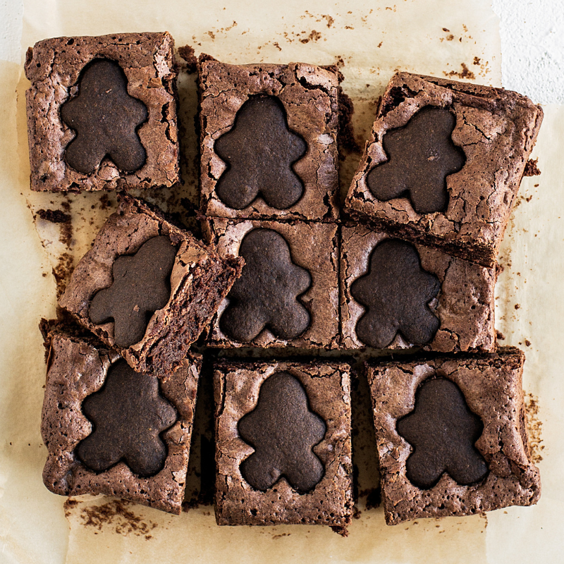 gingerbread brownies sliced into 9 slices, each topped with a mini gingerbread man cookie.