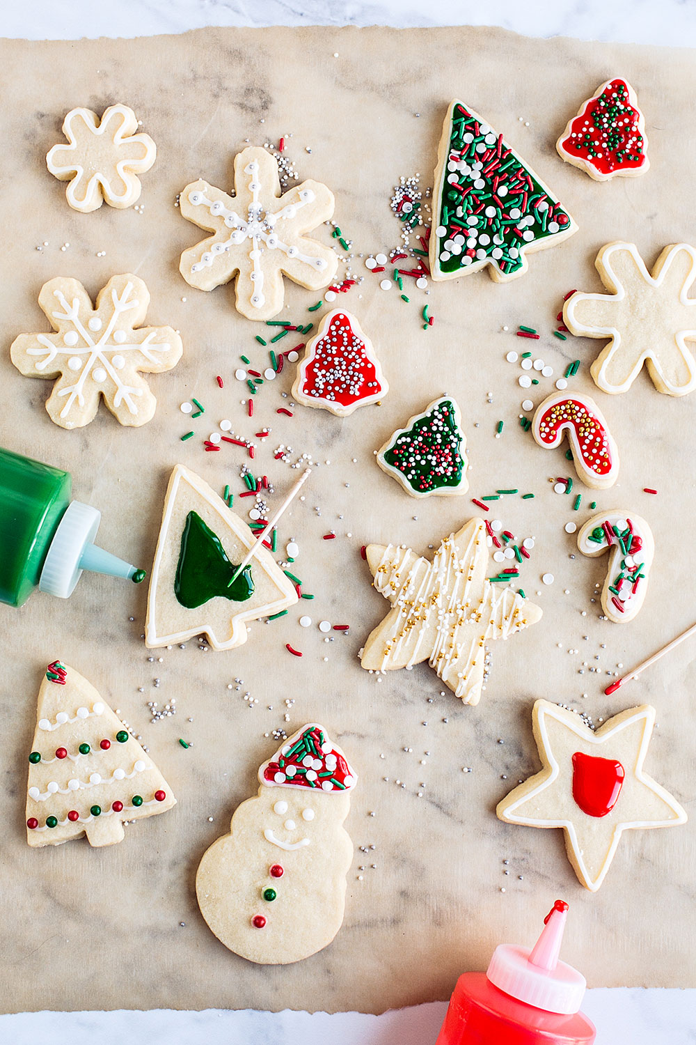 Easy Cut Out Sugar Cookies being decorated with red and green icing and sprinkles.