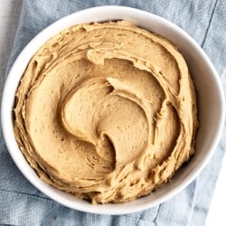 a white bowl filled with peanut butter buttercream frosting.