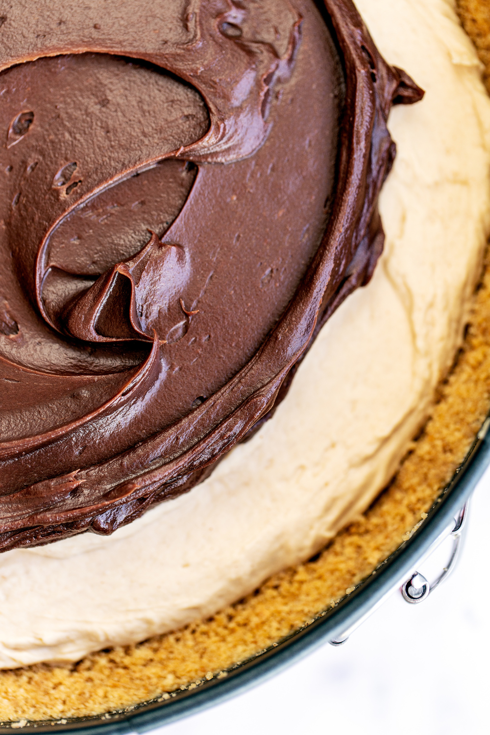 close look at the top of the peanut butter cheesecake, topped with rich chocolate ganache