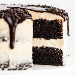 whole Guinness Chocolate Cake with Irish Buttercream with a ganache drip, with a slice taken out, so you can see the moist crumb of the cake inside.