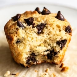 a chocolate chip muffin with its wrapper removed and a bite taken out.