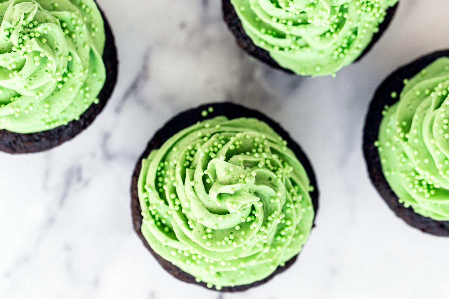 Four Mint Chocolate Cupcakes on a marble background.