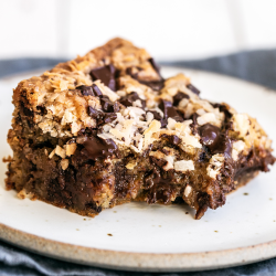 a slice of Chocolate Coconut Blondie on a white plate with a bite taken out.