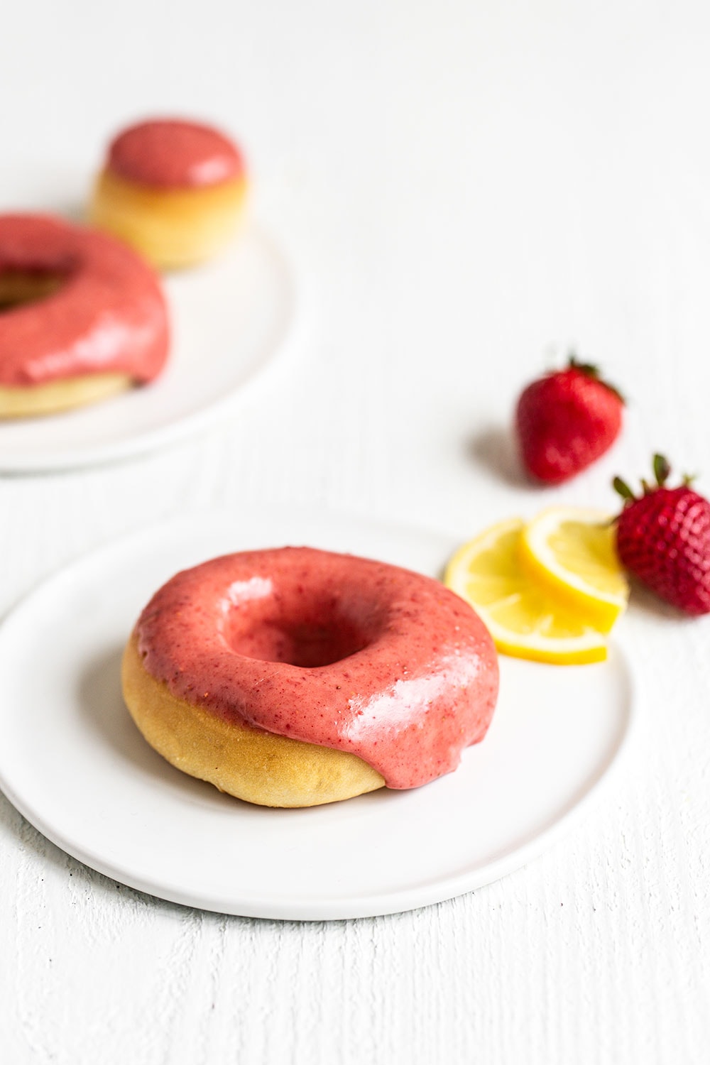 Doughnut on a plate with a slice of lemon and strawberries