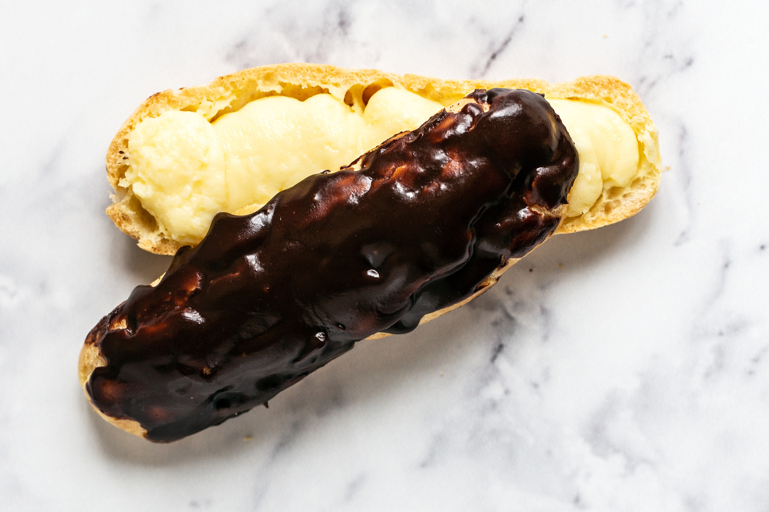 one eclair split in half to fill, waiting to be fully assembled to serve.