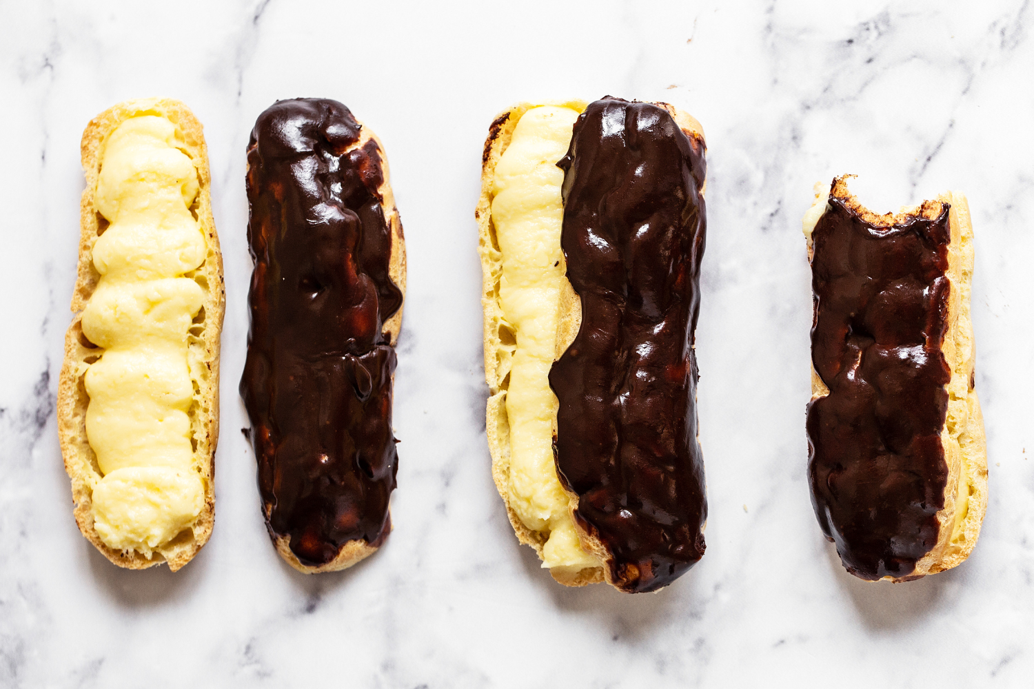 a lineup of filled, glazed chocolate eclairs.