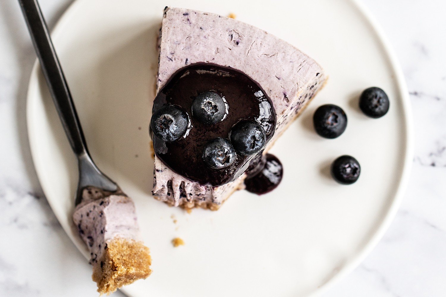 a slice of blueberry frozen pie on a white plate with a fork and a bite taken out.