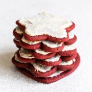 Stack of red velvet cut out cookies with cream cheese frosting