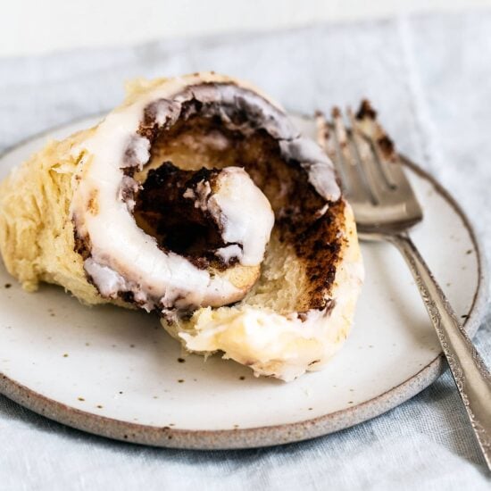 Gooey cinnamon roll on a plate with a fork