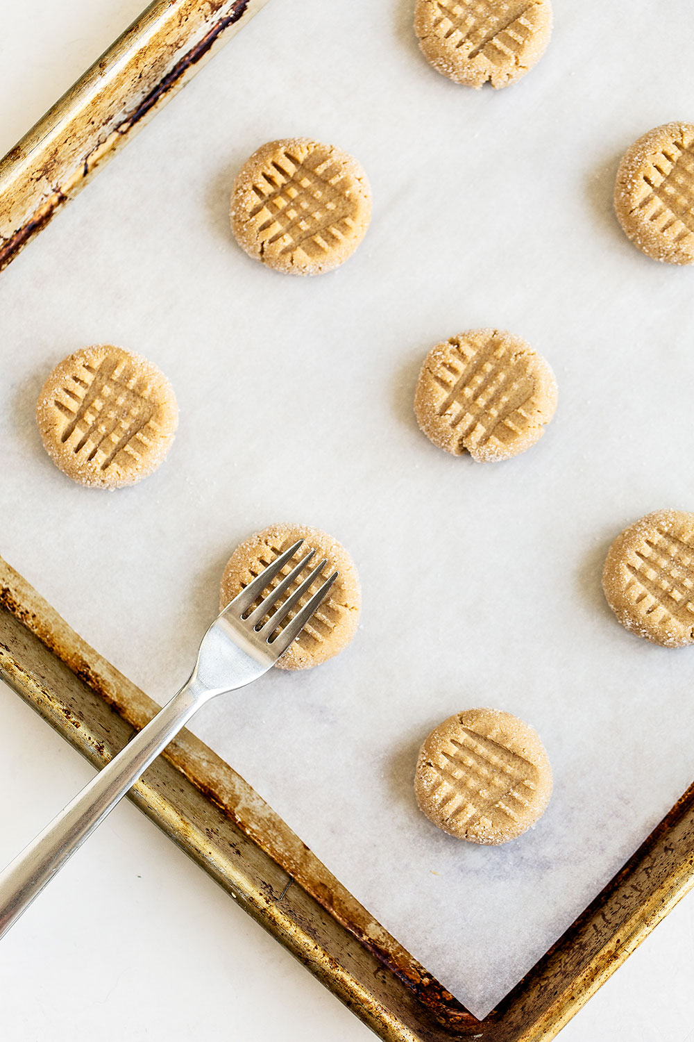 Pressing a fork into peanut butter cookies to make the cross indentation