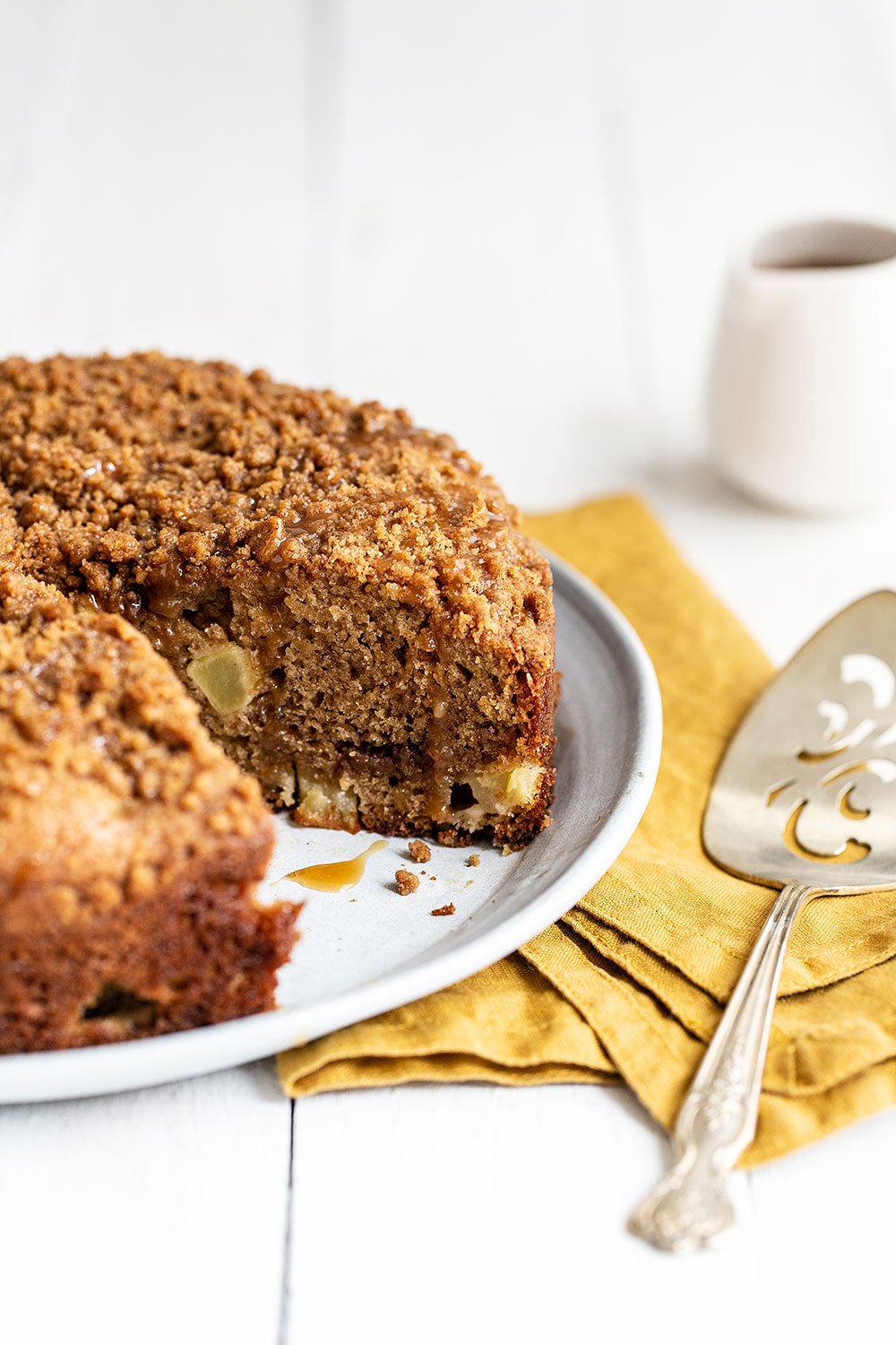 Easy caramel apple coffee cake on a platter with a serving spoon and a slice already removed