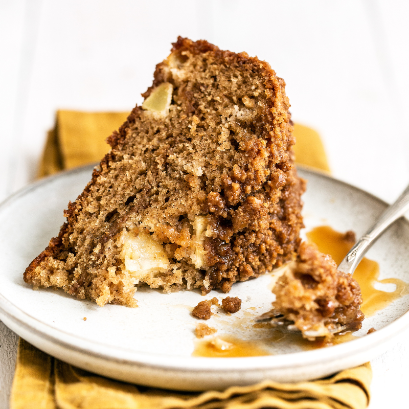 a slice of caramel apple coffee cake on a plate with a fork and a napkin underneath