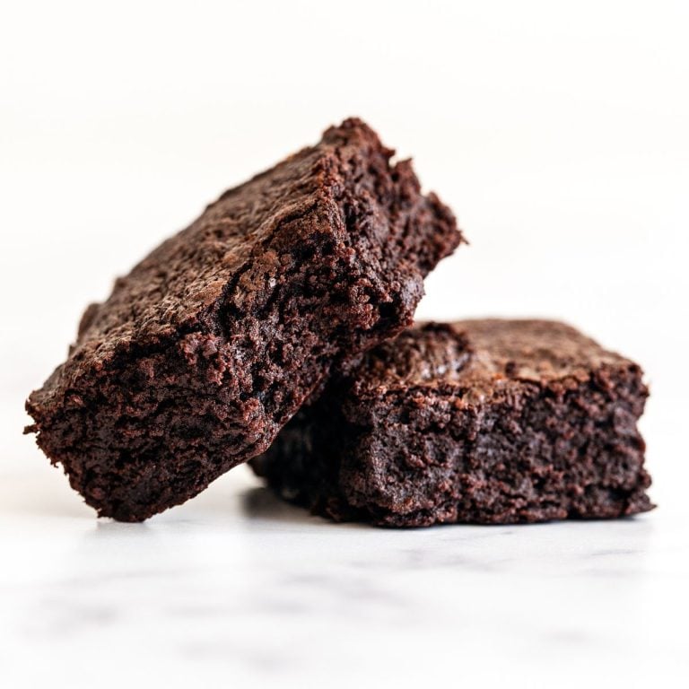 two slices of dark chocolate brownie on a white background.