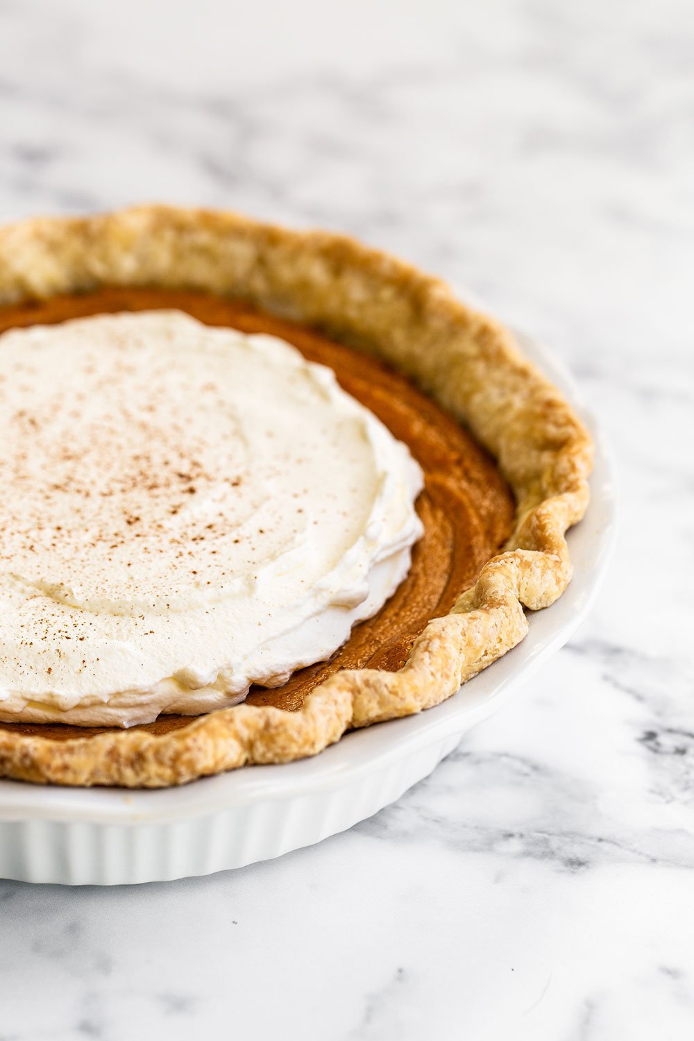 Homemade Brown butter sweet potato pie with whipped cream on a marble counter