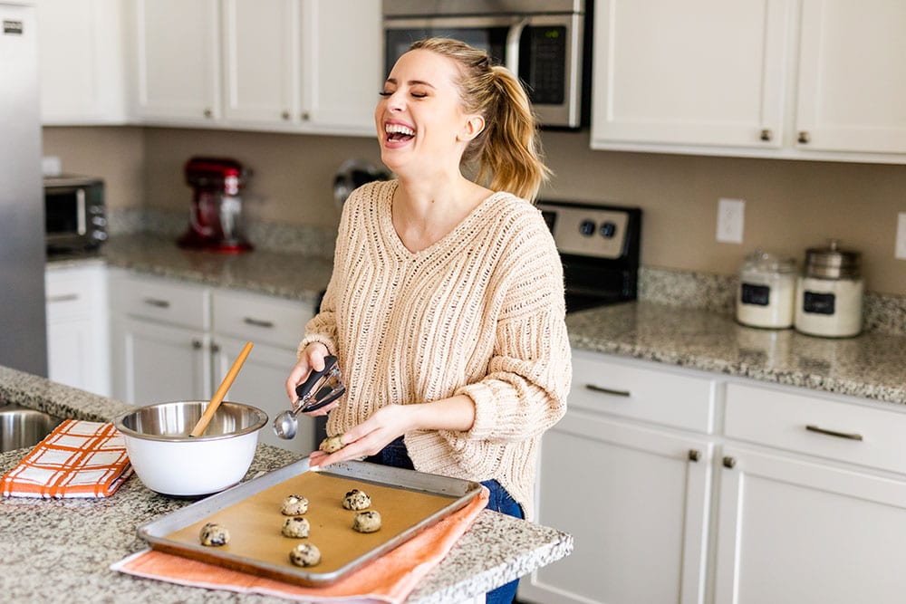 Author Tessa Arias baking cookies in her kitchen and laughing