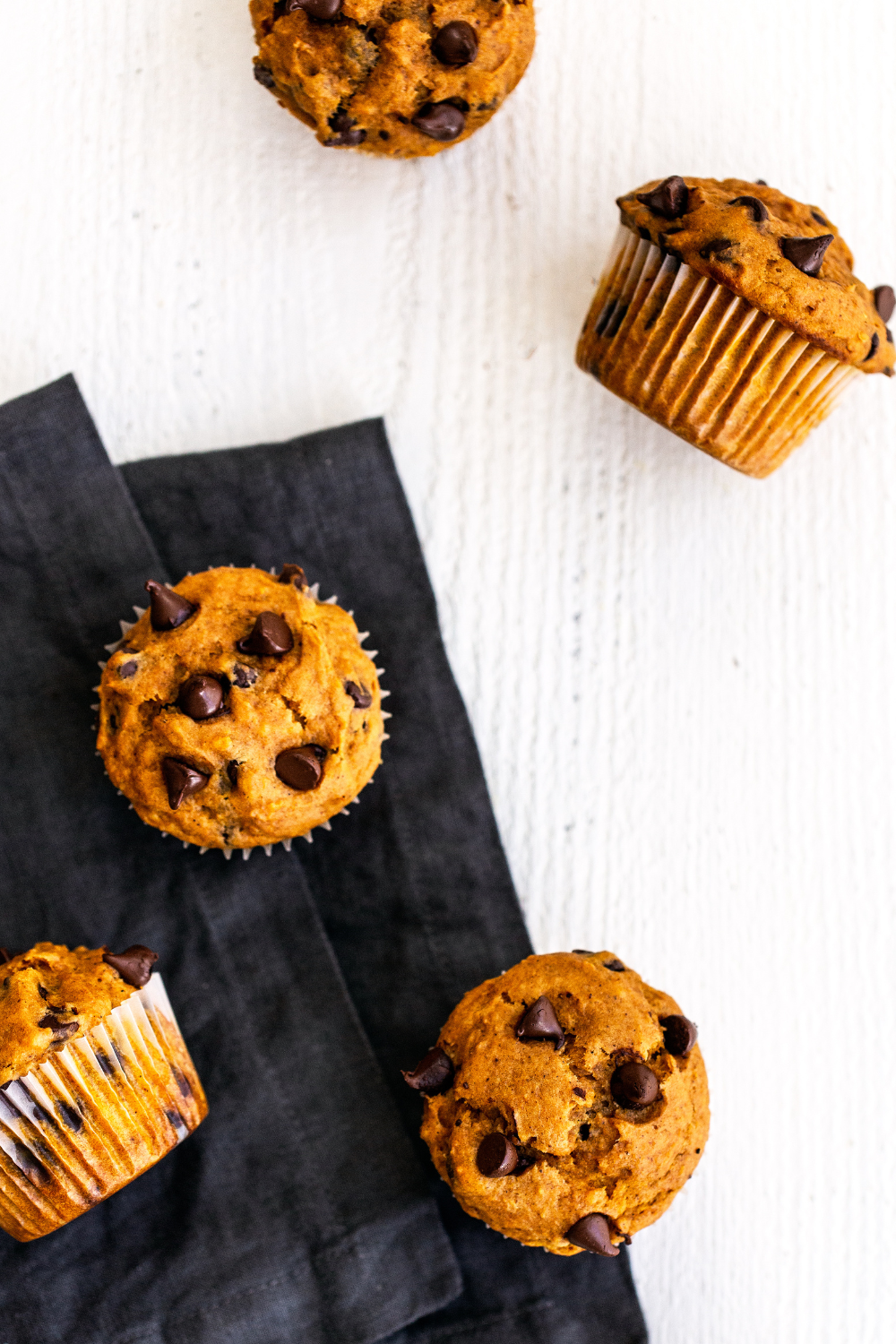 Pumpkin Chocolate Chip Muffins on a white background, with a black napkin, ready to serve