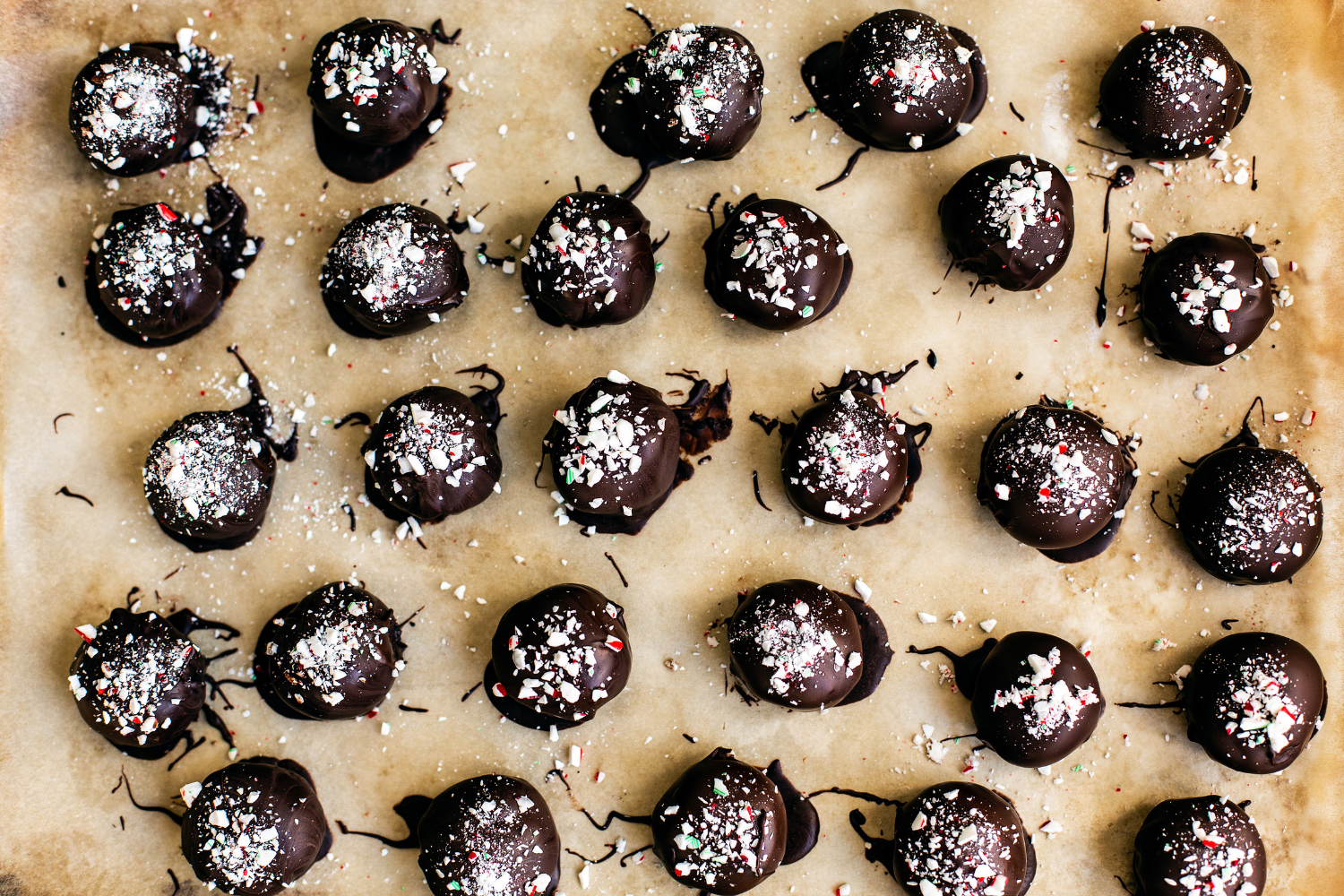 lots of Peppermint Oreo Truffles on a parchment-lined tray.