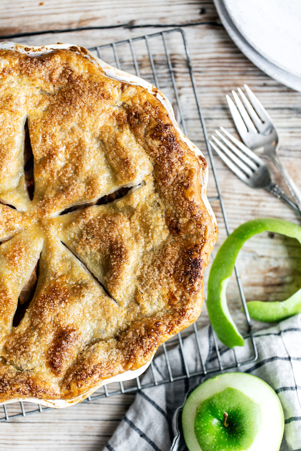 the baked apple pie with some granny smith apples and forks next to it.