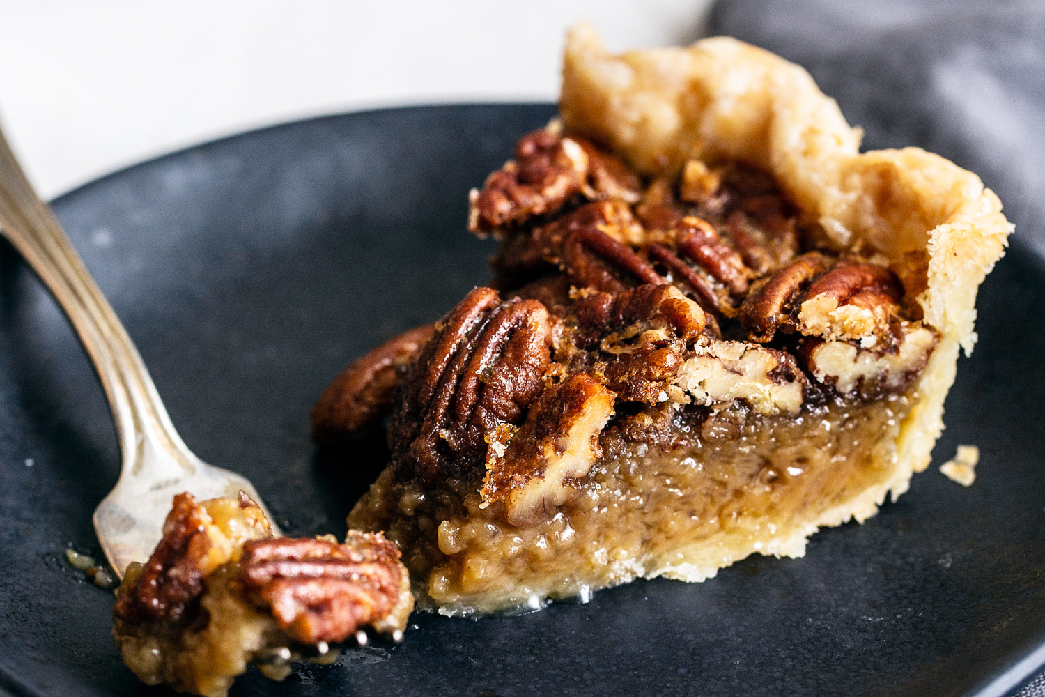 a perfect slice of pecan pie, on a plate with a fork, ready to serve.