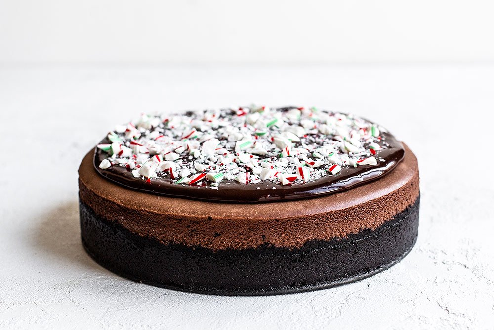 Chocolate cheesecake with Oreo crust, chocolate ganache topping, and crushed candy canes on top