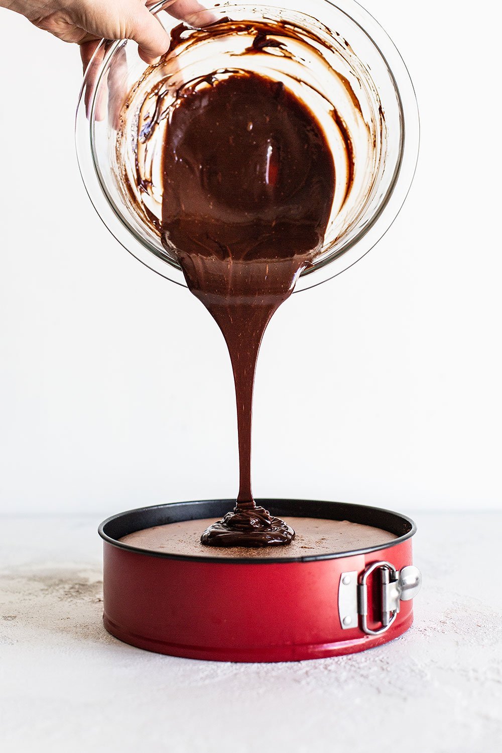 Chocolate ganache being poured onto chocolate peppermint cheesecake