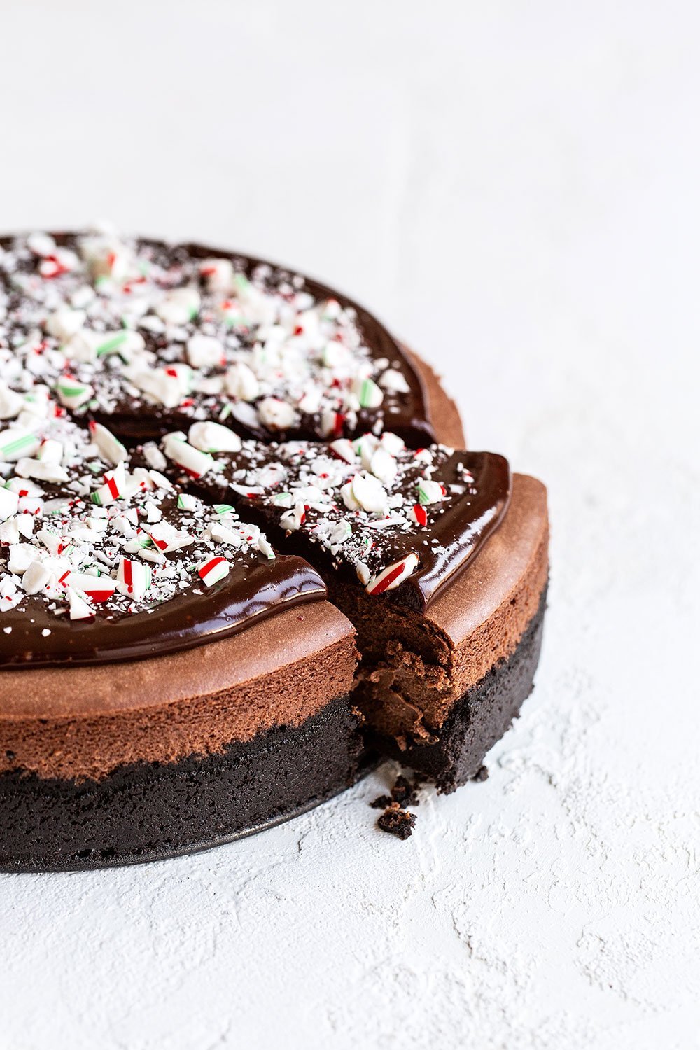 A slice being cut out of chocolate peppermint cheesecake