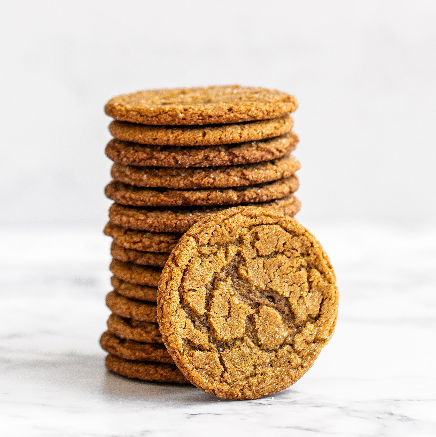 Stack of thin and crispy gingersnap cookies on a marble counter