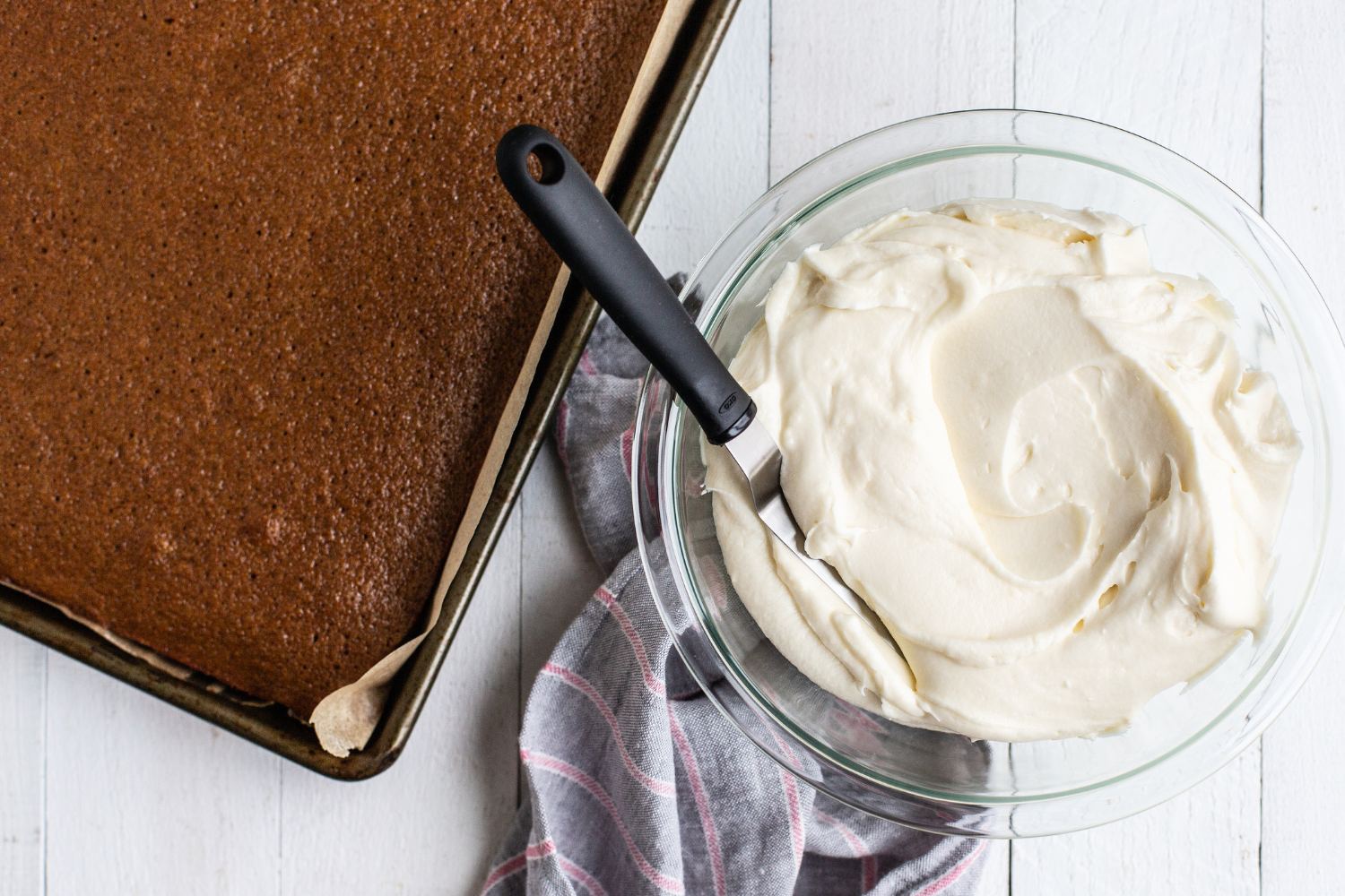 the whole Gingerbread Sheet Cake in its pan, beside a bowl of cream cheese frosting, ready to ice.