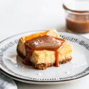Salted caramel cheesecake square on a plate with caramel sauce on top