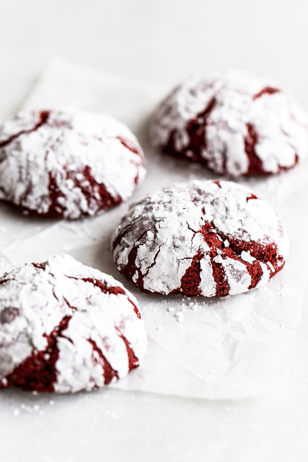 four baked Red Velvet Crinkle Cookies on a tray.