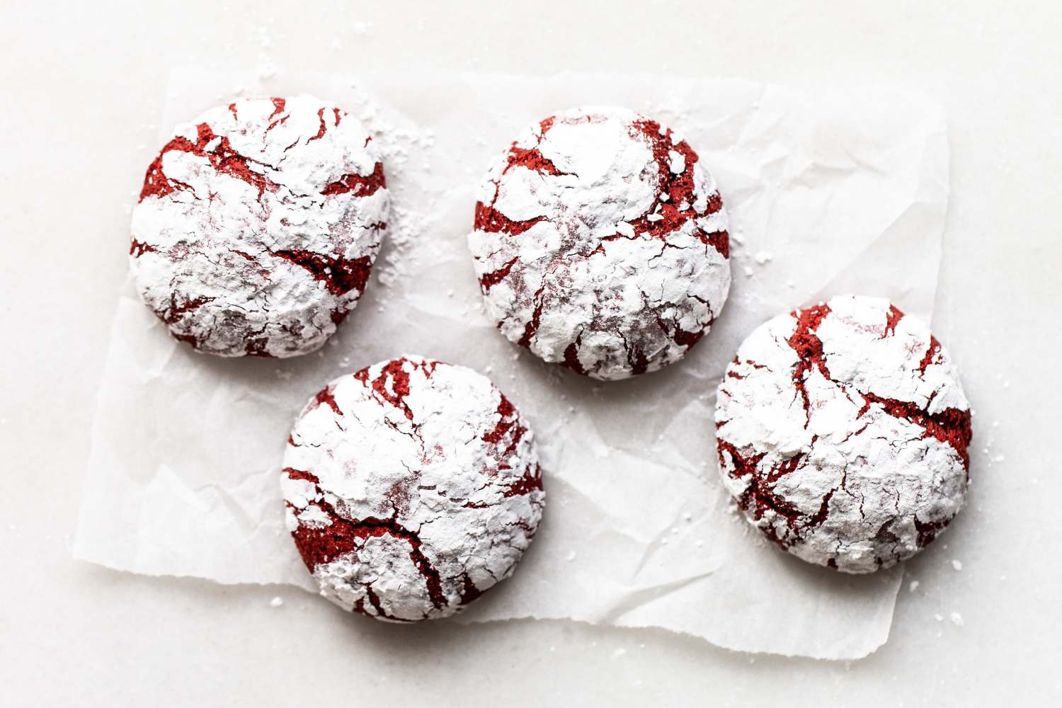 a few Red Velvet Crinkle Cookies on parchment paper.