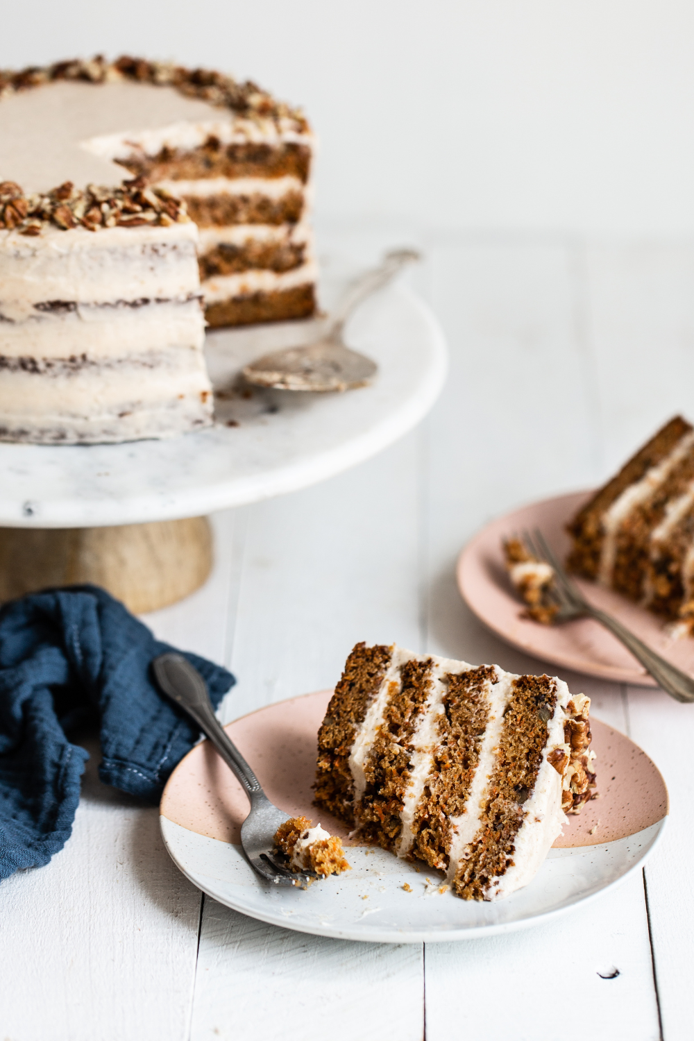 the whole carrot cake on a cake stand, with a slice taken out and on a plate to serve.