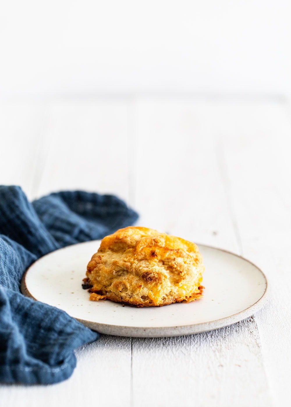 Flaky cheesy cheddar biscuit on a plate with a napkin