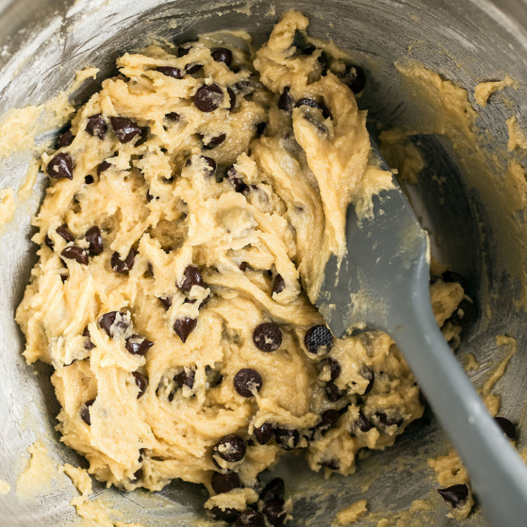bowl of chocolate chip cookie dough in a metal bowl with a spatula.
