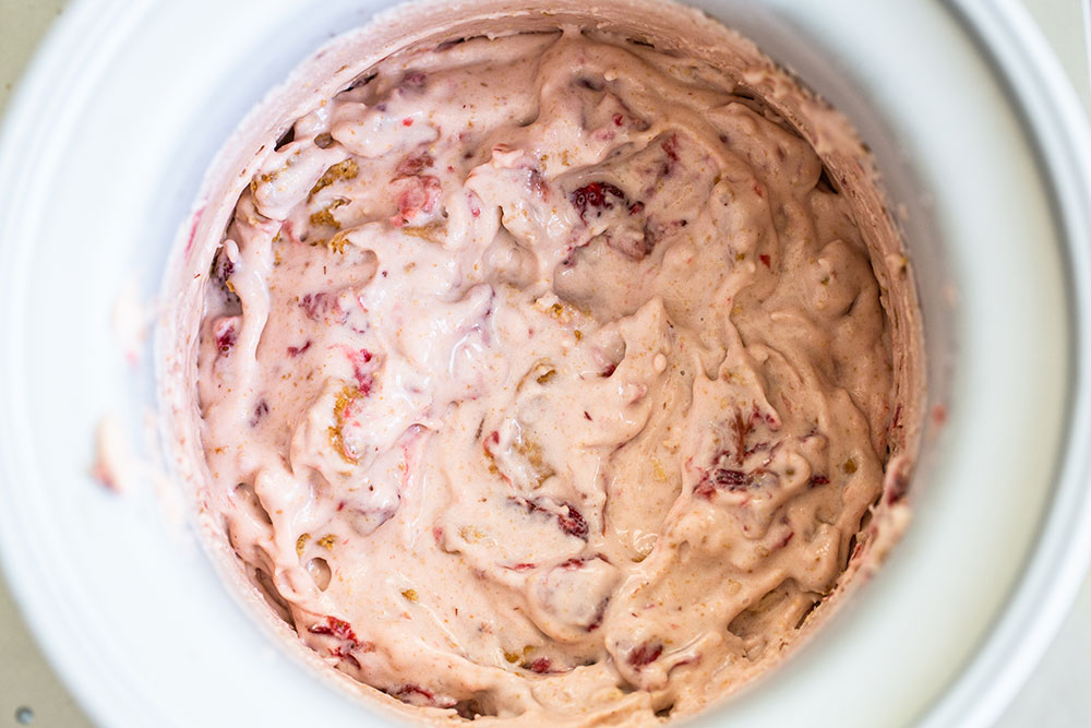 bowl of strawberry cheesecake ice cream in the ice cream machine, churned and ready to place in the freezer