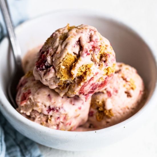 scoops of roasted strawberry cheesecake ice cream in a bowl with a spoon, ready to serve